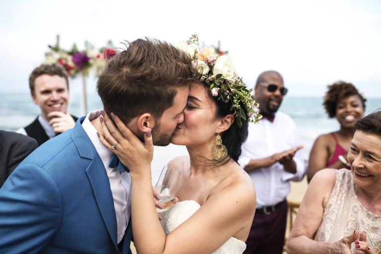 A newly married couple sharing a kiss as their guests celebrate around them