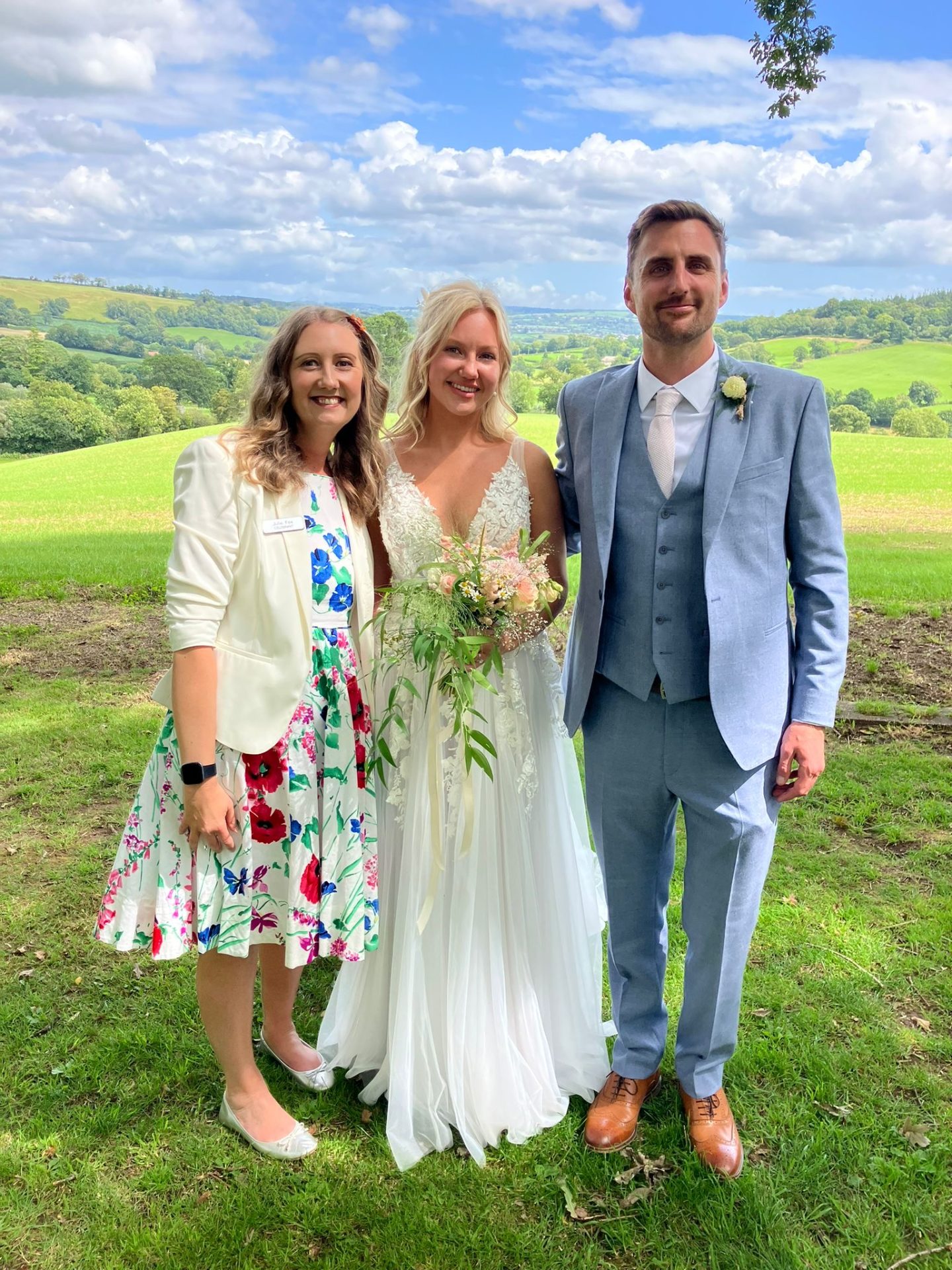 A bride and groom with a guest in the meadow after their outdoor ceremony at Burrow Farm Gardens