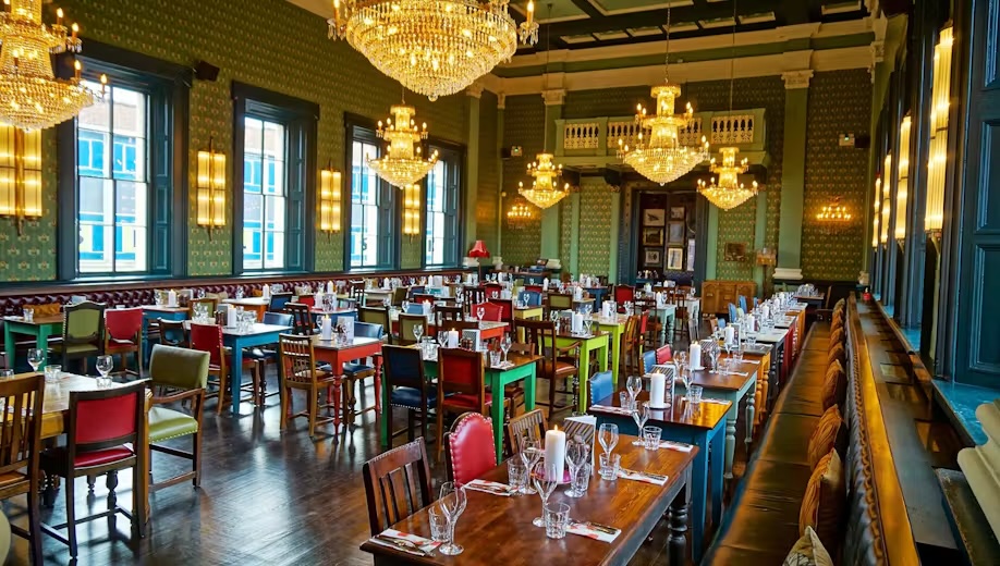 The grand dining room at Cosy Club Exeter, with chandeliers and green panelled walls