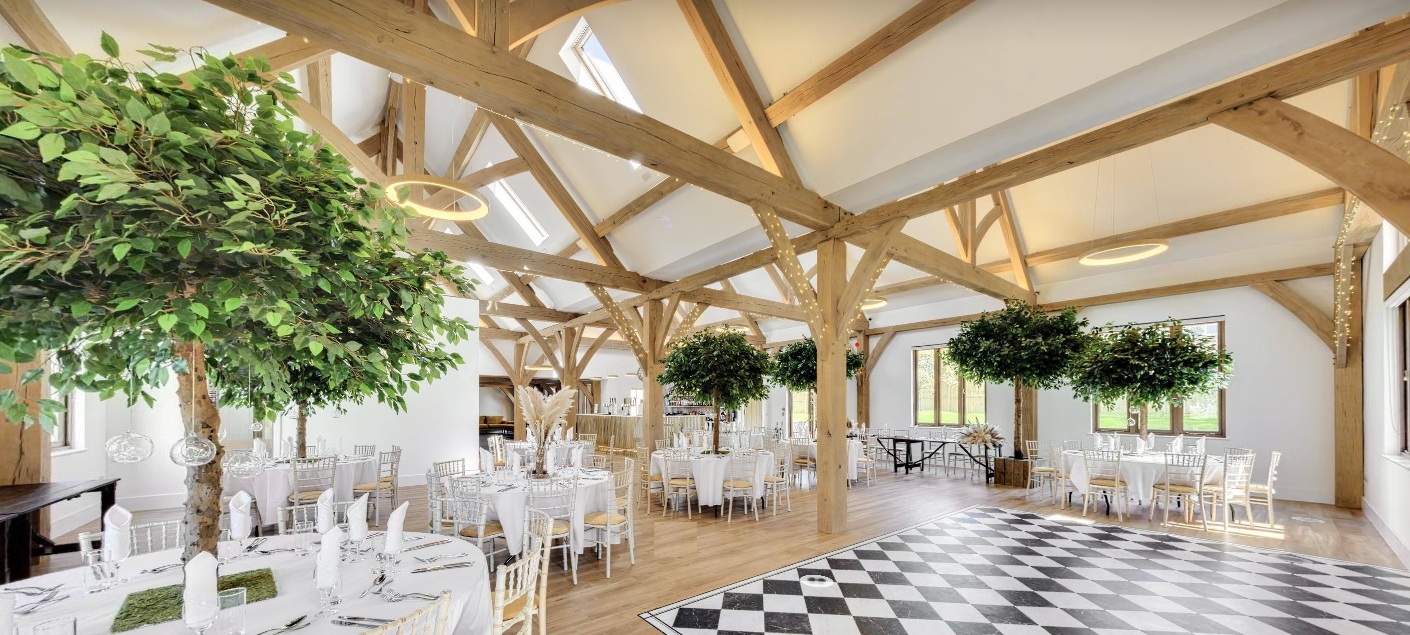 Tables laid for a wedding inside the light, oak-framed Glebe Barn