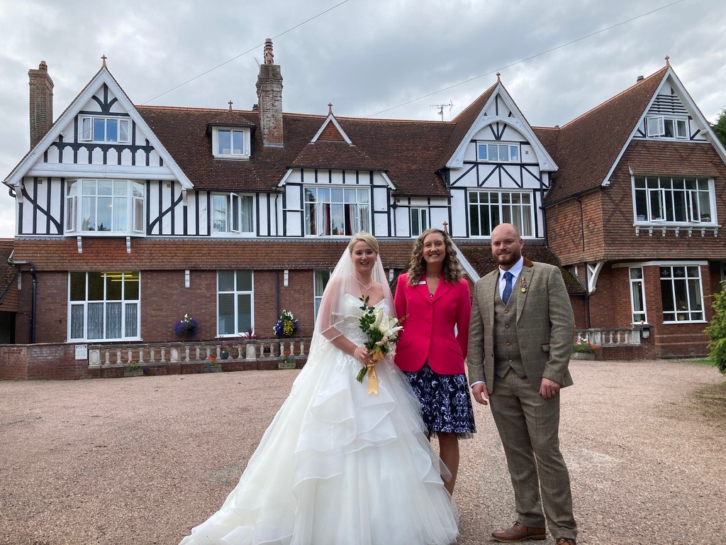 A bride and groom with celebrant Julie Fox outside The Grange Court Hotel in Rockbeare