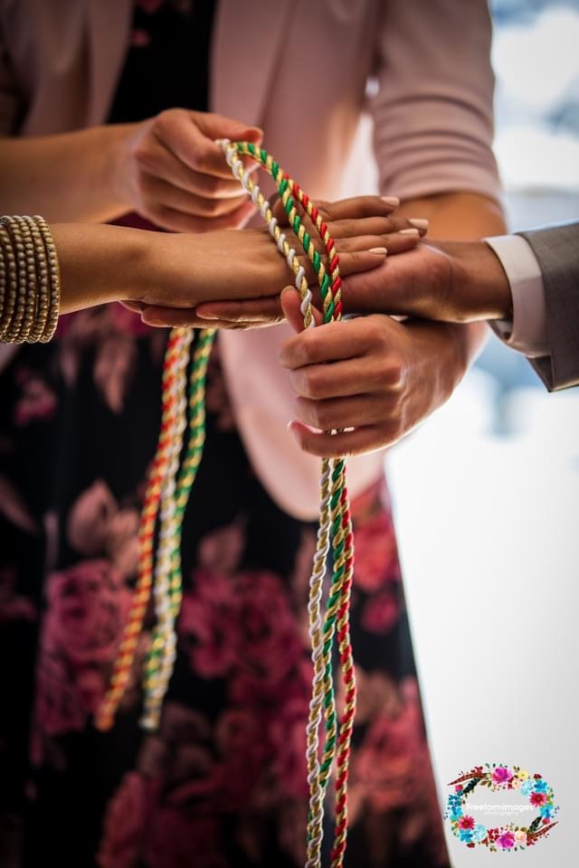 Close-up of a couple's hands bound with handfasting cords
