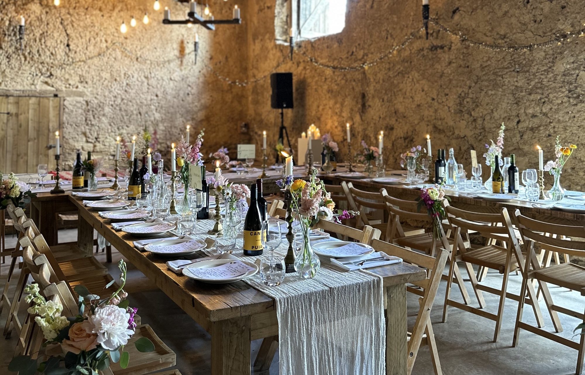 Long tables set for a wedding breakfast in the stone barn at Higher Eggbeer Farm