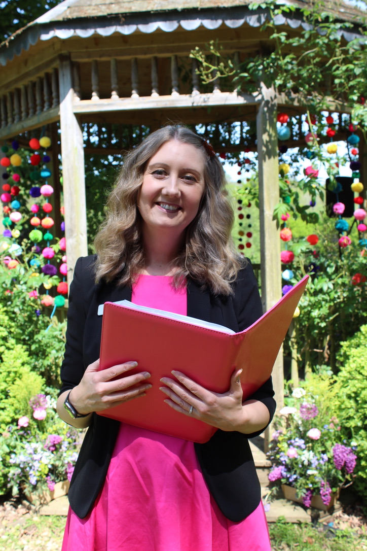 Julie Fox holding her ceremony folder in the gardens at Netherton Hall, Farway