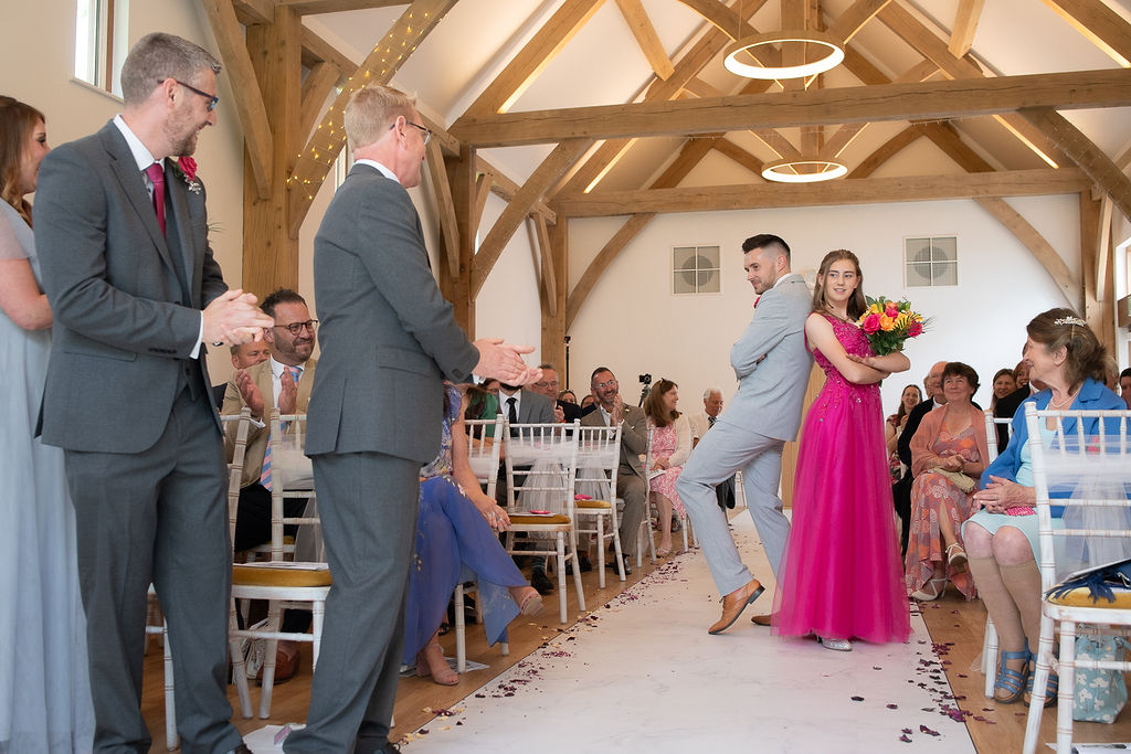 The bridal party coming down the aisle at Julie Fox's wedding at Glebe Barn