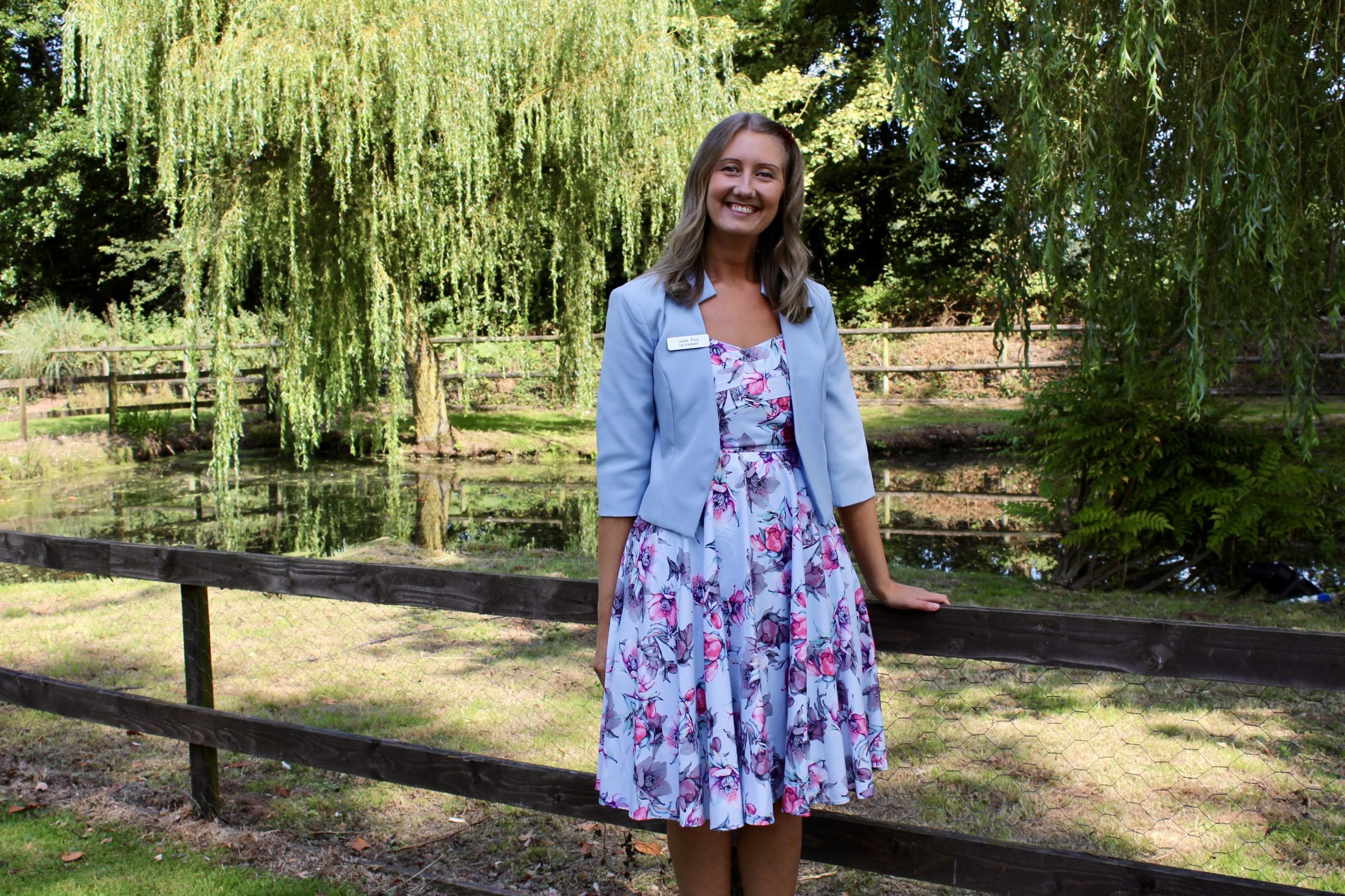 Wedding celebrant Julie Fox smiling by a willow-fringed pond at a Devon wedding