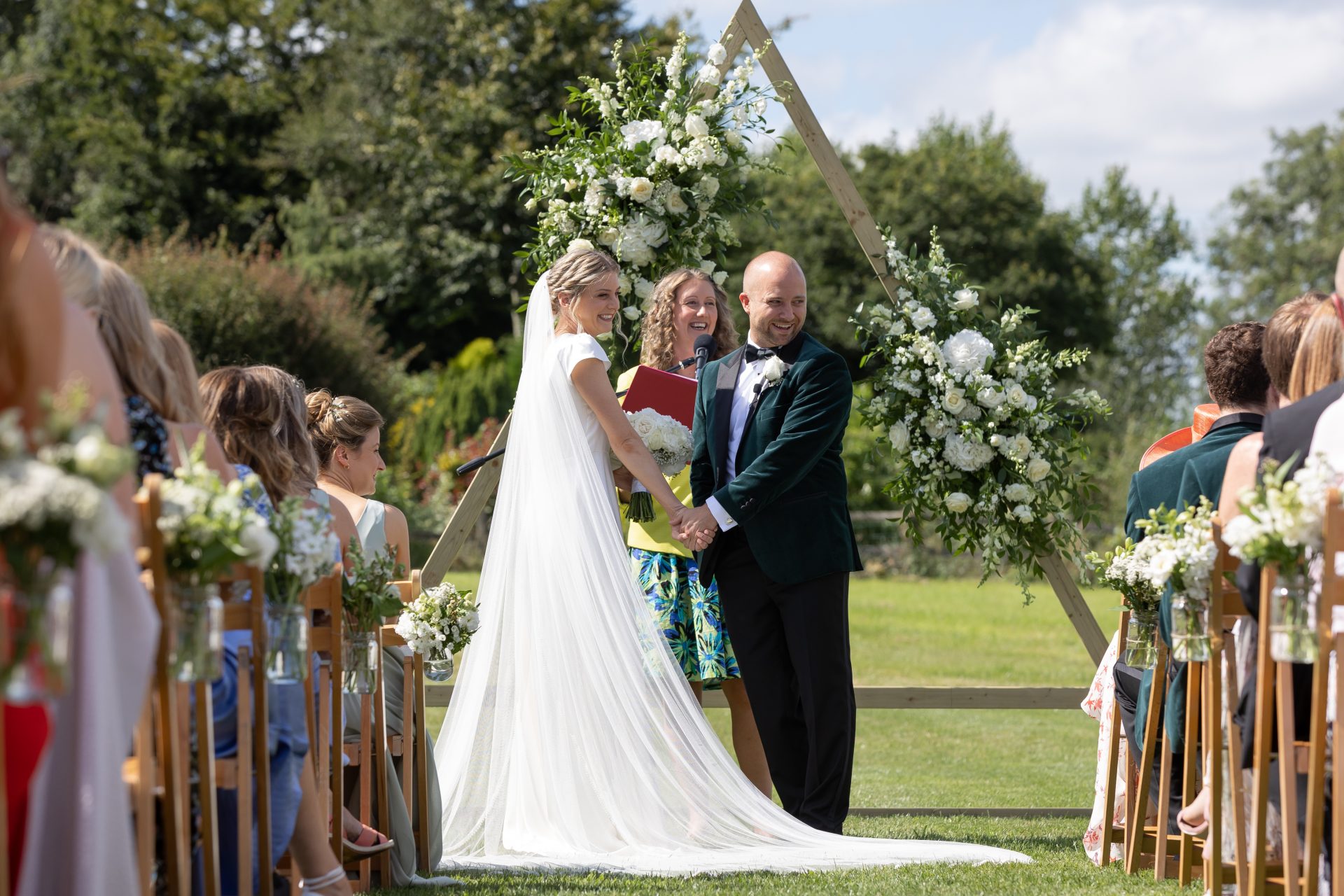 Lucy and Beau at the end of the aisle beneath a floral arch, Stoodleigh