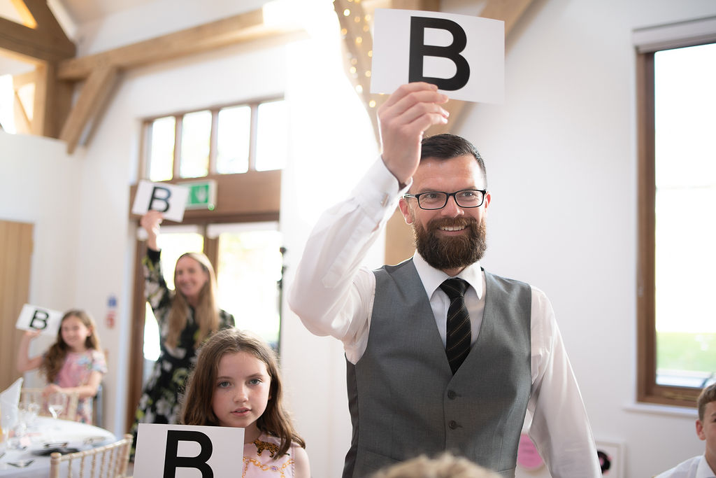 The groom holding up an answer card during the Mr and Mrs game at Julie Fox's wedding