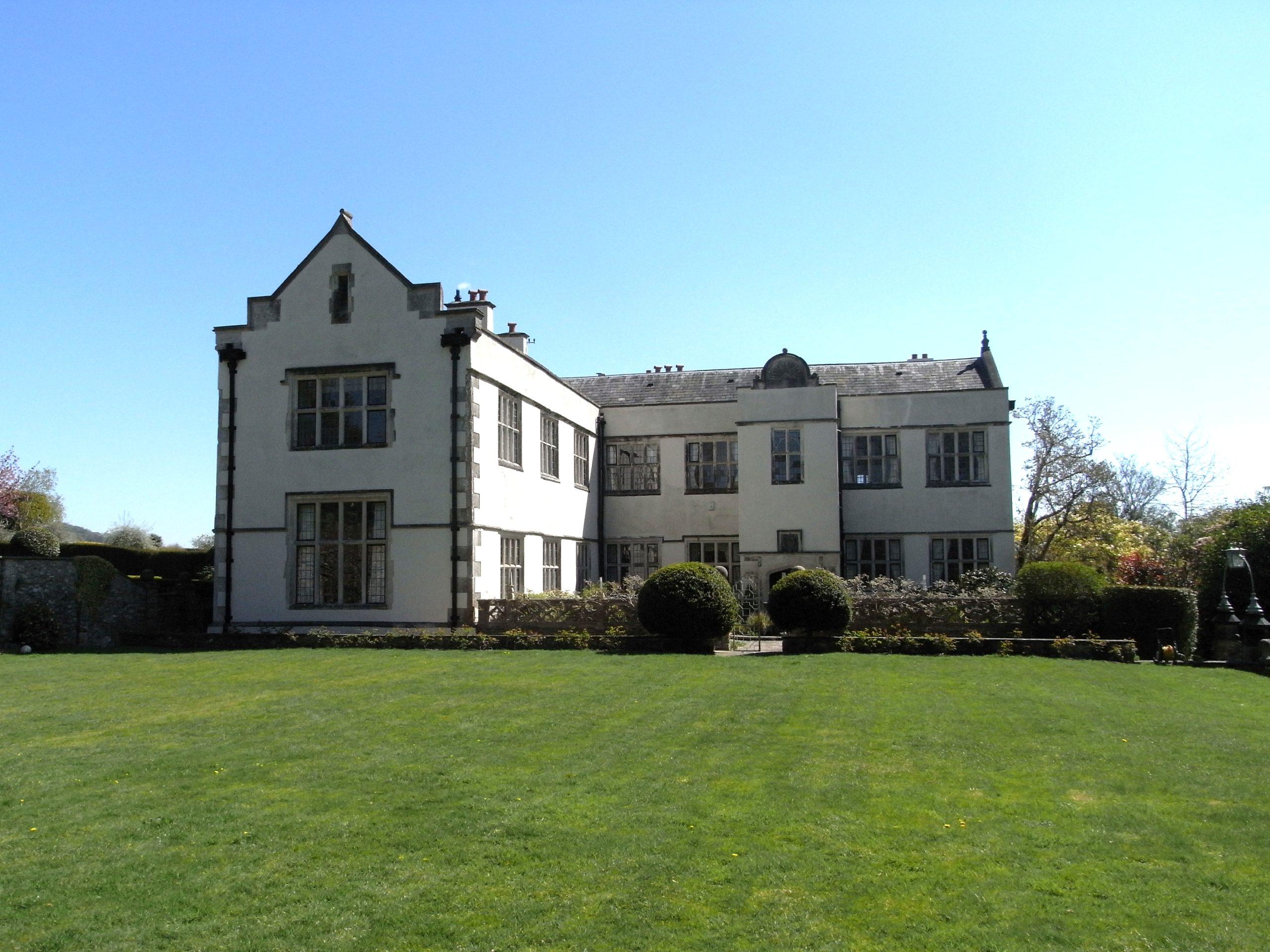 The west front of Netherton Hall and its lawn under a blue sky