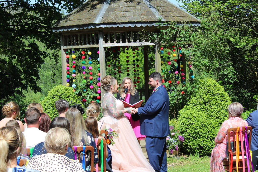 A couple at their ceremony beside the garden gazebo at Netherton Hall, surrounded by guests