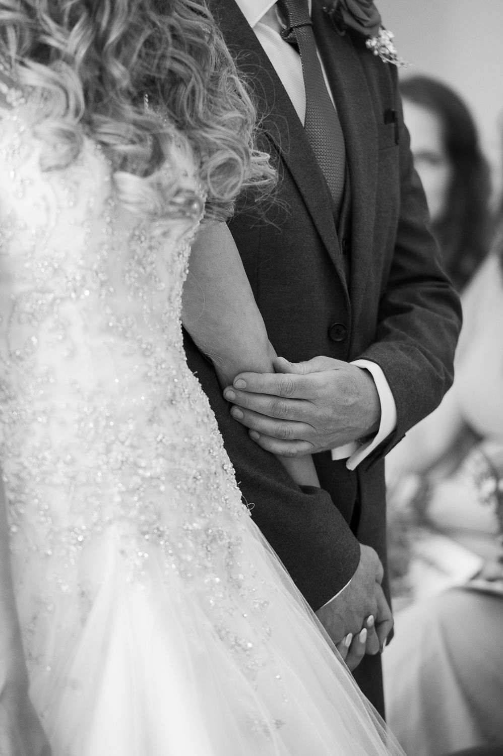 Black and white photo of a bride and groom holding hands