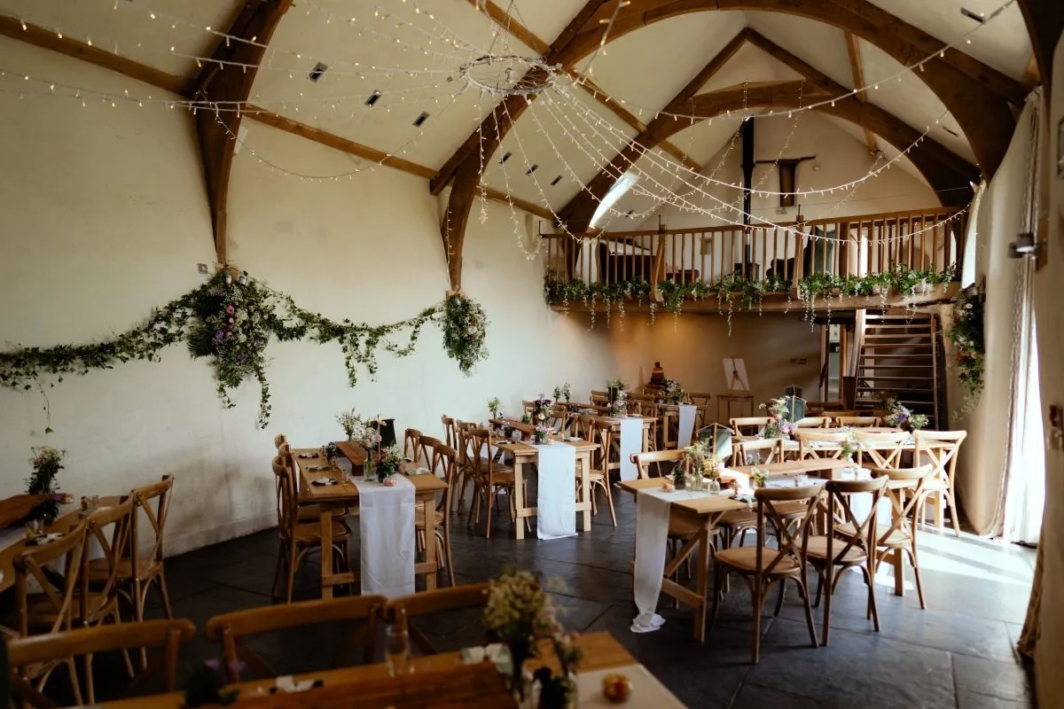 Wedding tables beneath the oak beams and gallery at The Oak Barn
