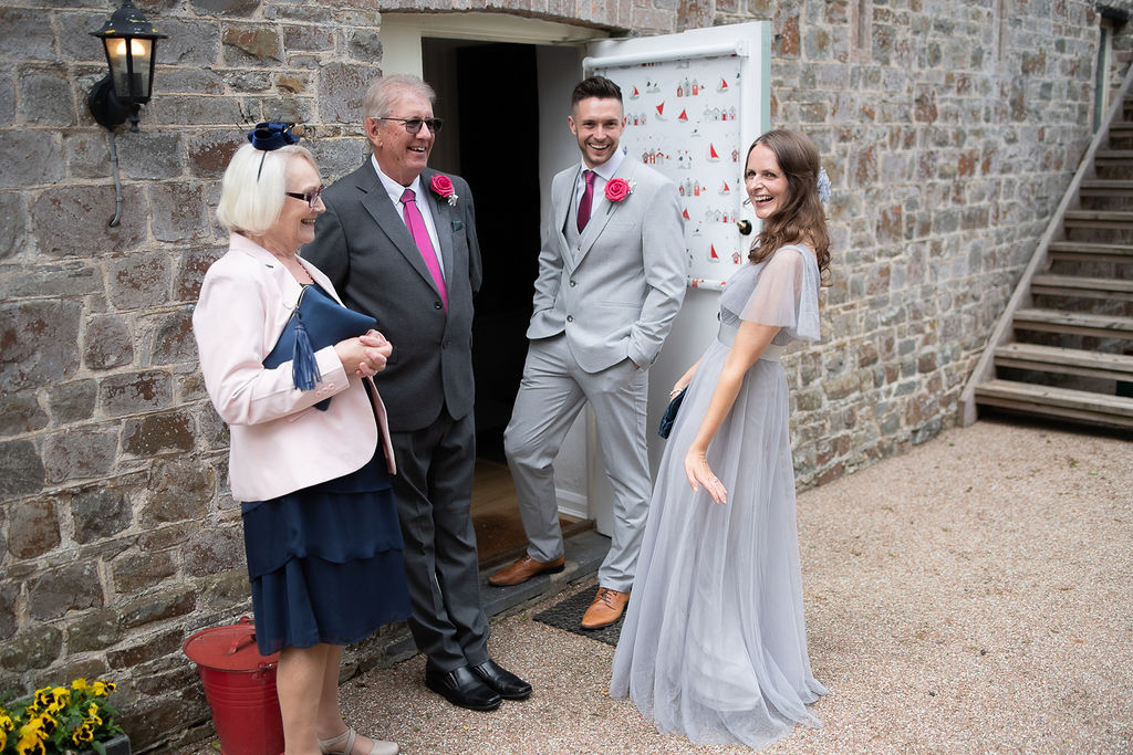 A bride, groom and their family outside a stone doorway on the wedding day