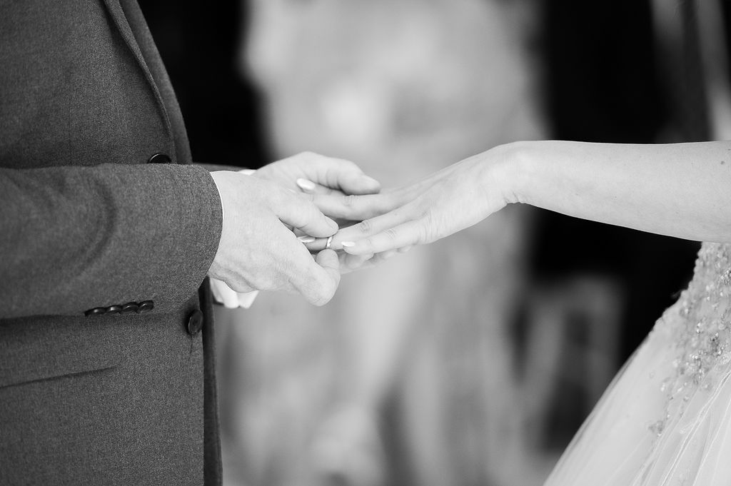 Close-up of a wedding ring exchange, in black and white